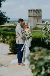 A bride and groom embracing in the landscaped gardens of Rowton Castle, a luxury Shropshire wedding venue.