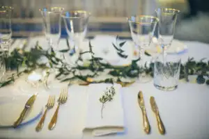 Elegant wedding table setting with gold cutlery, glassware, candles, and greenery at Rowton Castle.