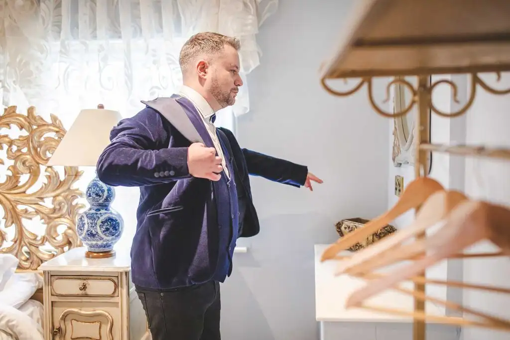 Groom adjusting his jacket while getting ready on the wedding morning