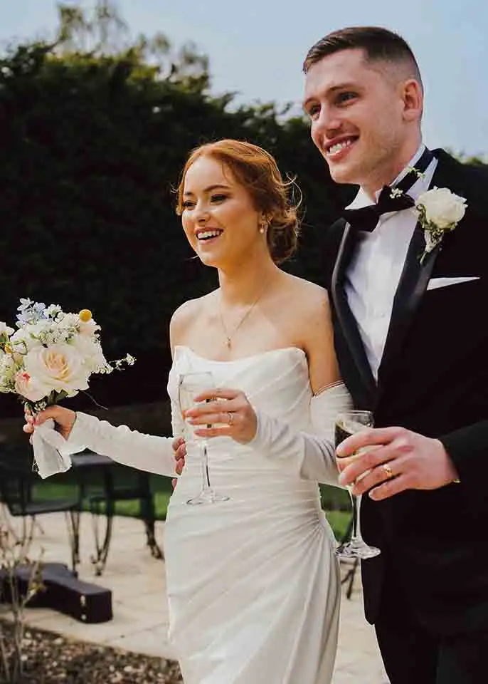 Bride and groom holding champagne glasses during wedding celebrations at Rowton Castle