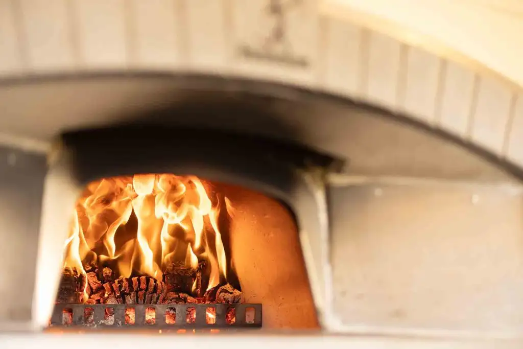 Wood-fired pizza oven with flames used for evening wedding food at Rowton Castle