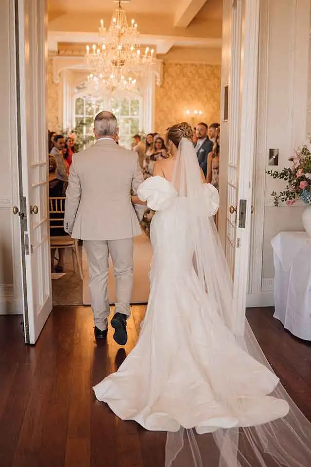 Bride entering the ceremony room with her father at Rowton Castle wedding venue