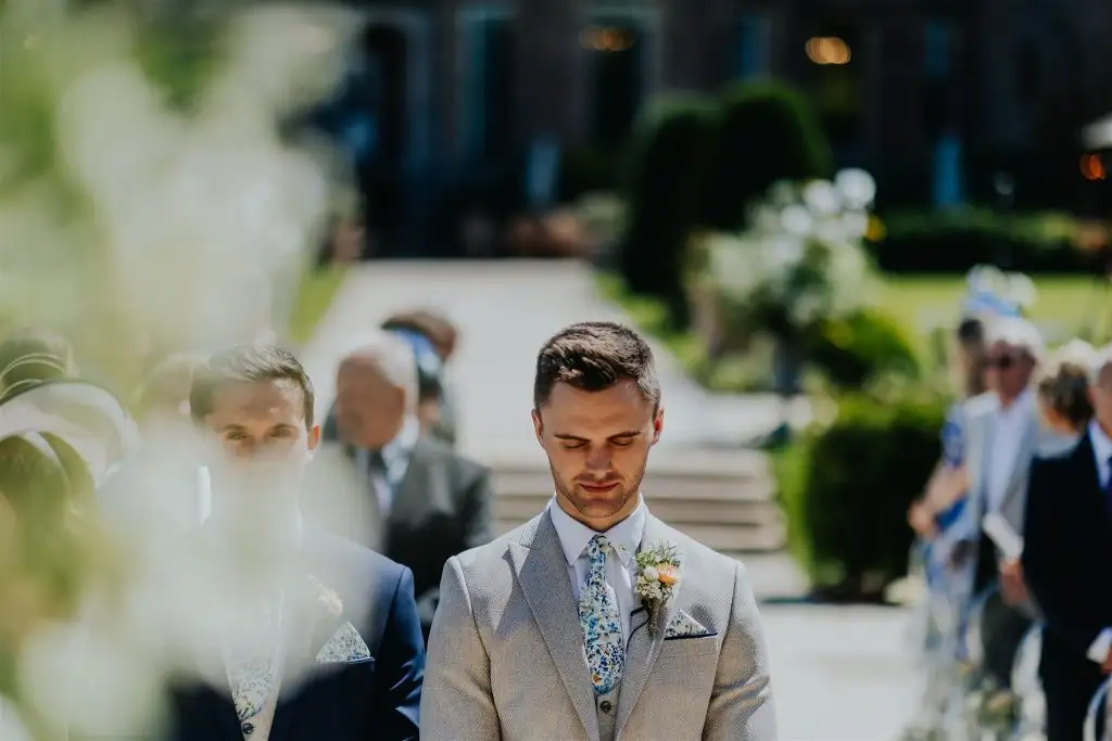 Groom waiting for the ceremony to begin during an outdoor wedding at Rowton Castle