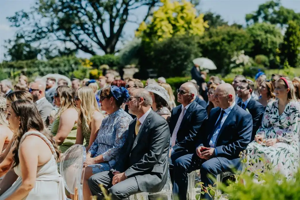 Wedding guests seated outdoors watching the ceremony at Rowton Castle gardens