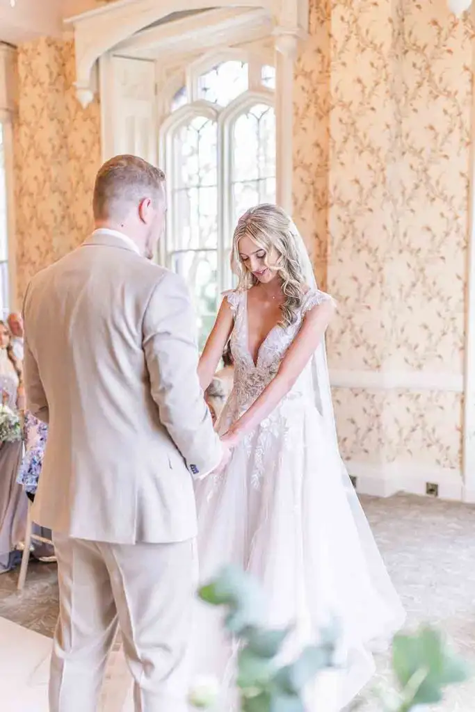 Bride and groom holding hands during their indoor wedding ceremony at Rowton Castle