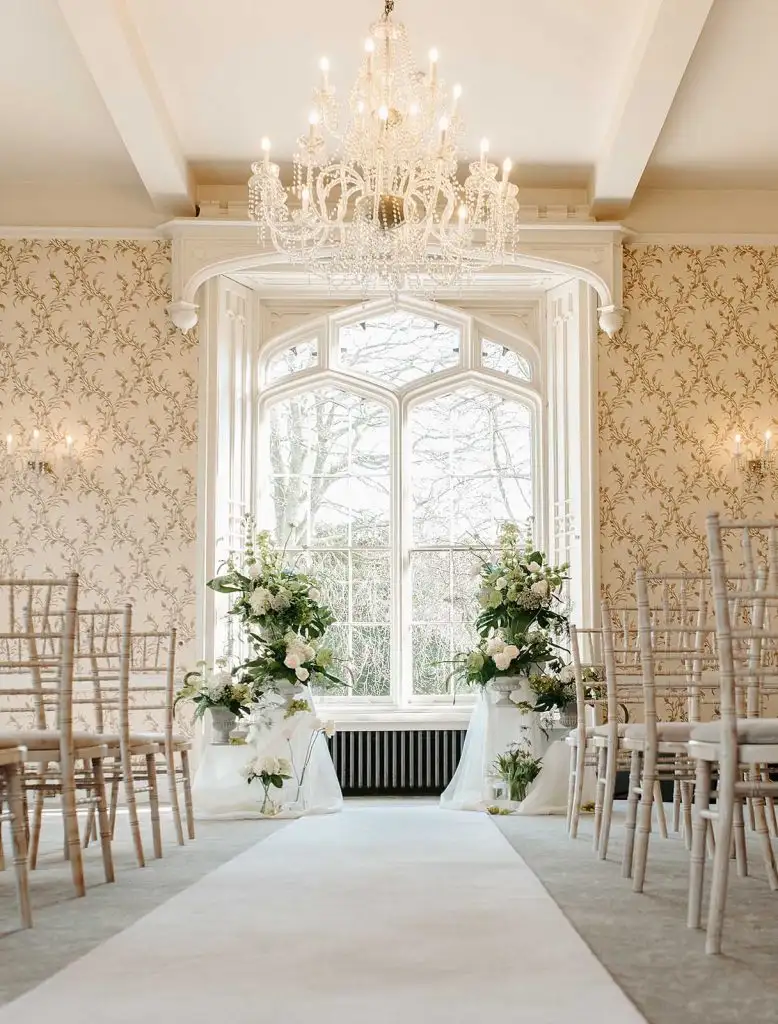 Elegant indoor wedding ceremony setup at Rowton Castle with chandelier, aisle runner and floral arrangements