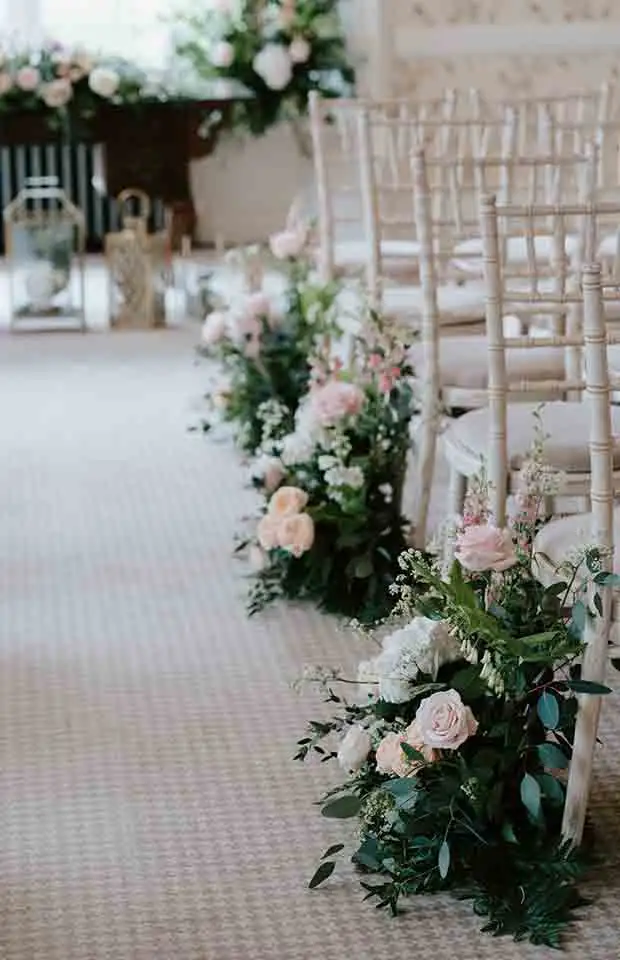Floral aisle decorations beside chiavari chairs during a Rowton Castle wedding ceremony
