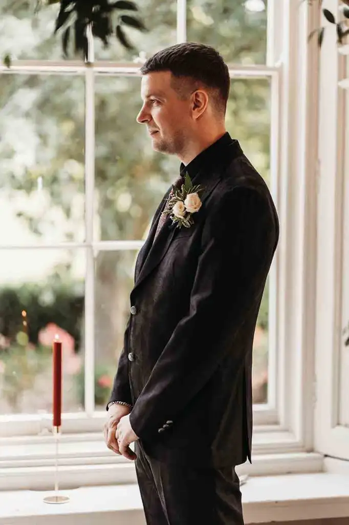 Groom waiting by the ceremony room window before the wedding ceremony at Rowton Castle