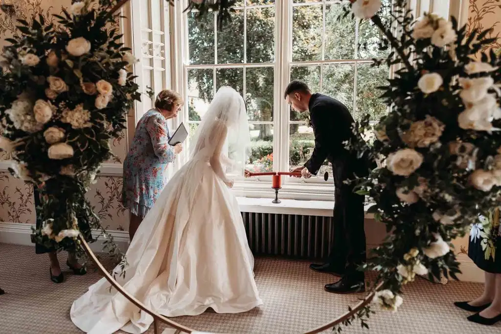 Bride and groom lighting a unity candle during their wedding ceremony at Rowton Castle